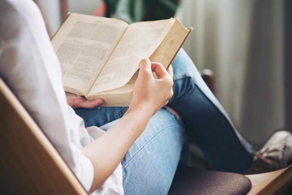 A person sits relaxed, engrossed in reading an open book