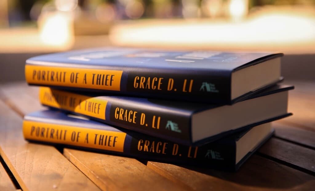 Three books "Portrait of a Thief" on a wooden bench