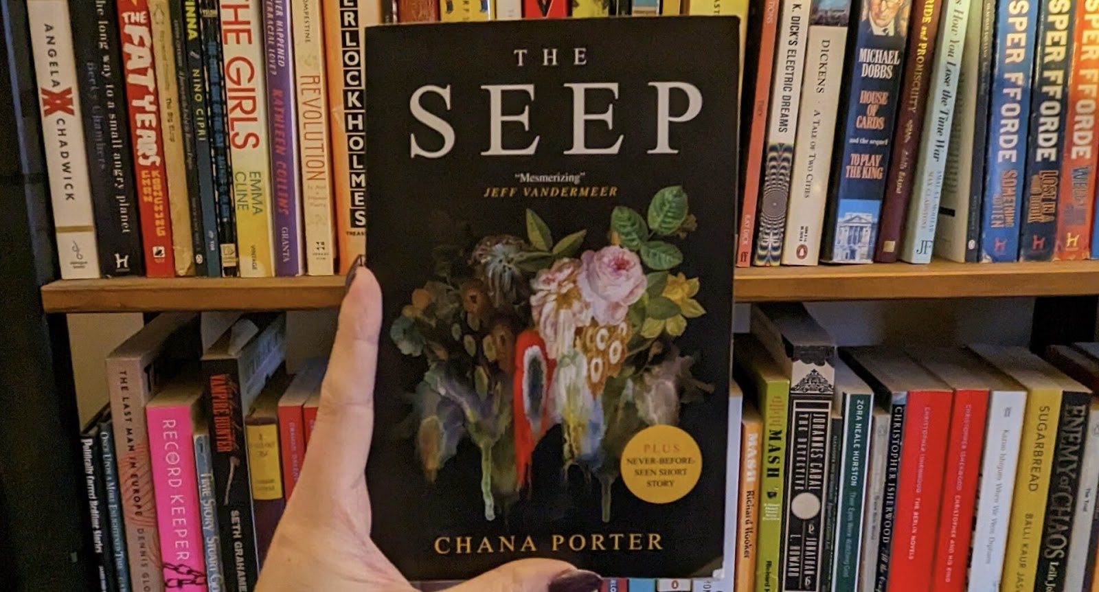 Hand holding a book against the background of a shelf with books