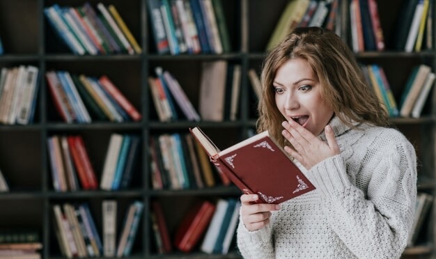 Emotional girl reading a book in the library