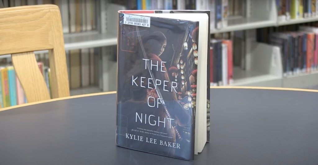 The book "The Keeper of Night" on the table in the library