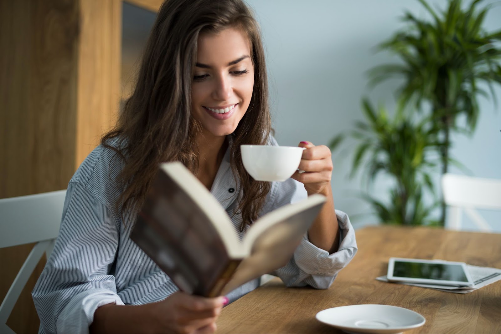 Woman reading book and drinking coffee