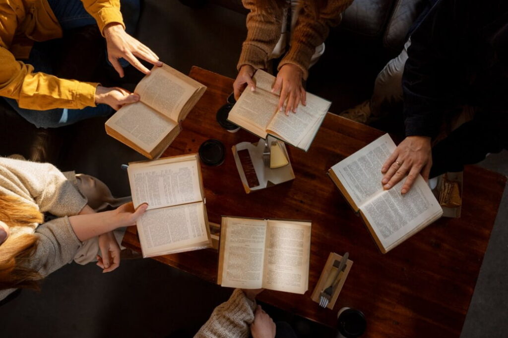 A group of people gathered around a table, reading and discussing books together